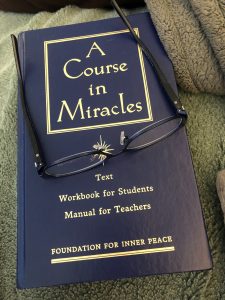 A Course in Miracles textbook with reading glasses resting on its cover