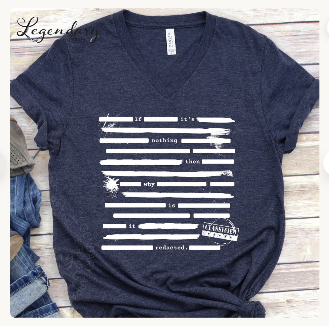 flat lay of navy blue T-shirt with white text peeking from lines covering redacted sections: If it's nothing then why is it redacted?