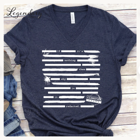 flat lay of navy blue T-shirt with white text peeking from lines covering redacted sections: If it's nothing then why is it redacted?